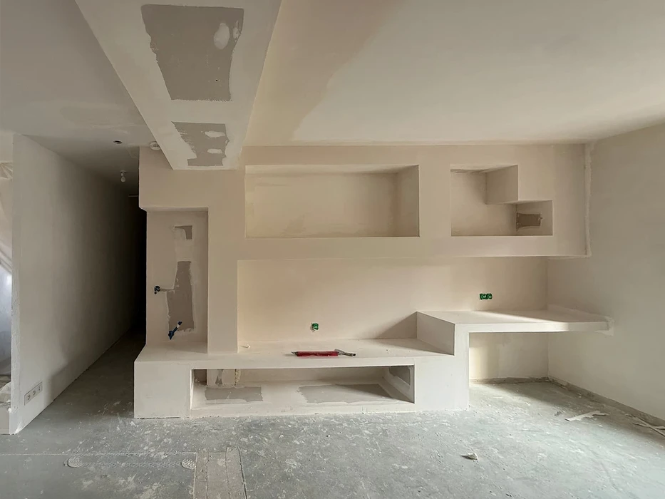 Chantier de construction résidentielle en cours, maison individuelle moderne avec façade blanche, toit en tuiles rouges et balcon à garde-corps métallique décoratif