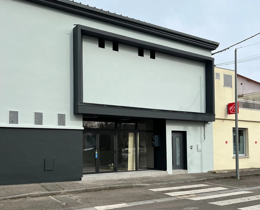 Chantier de construction résidentielle en cours, maison individuelle moderne avec façade blanche, toit en tuiles rouges et balcon à garde-corps métallique décoratif