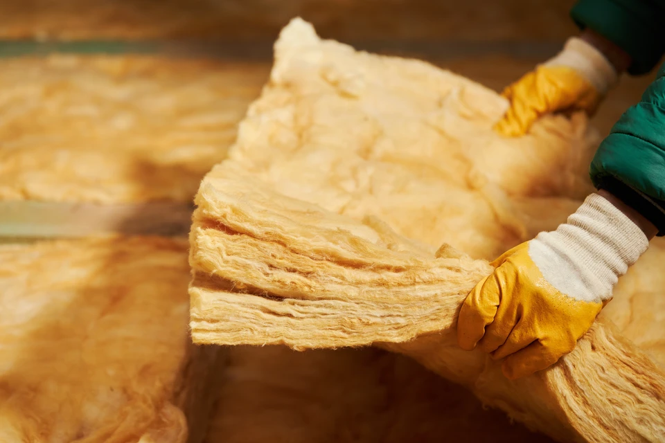 Homme équipé d'un masque respiratoire FFP2 avec valves jaunes et lunettes de protection travaillant au plafond d'un bâtiment