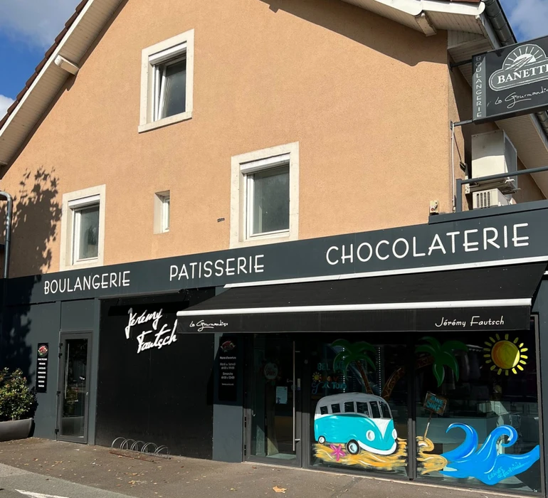 Façade d'immeuble résidentiel moderne avec porte d'entrée vitrée à carreaux et six fenêtres à volets roulants blancs disposées symétriquement sur deux étages