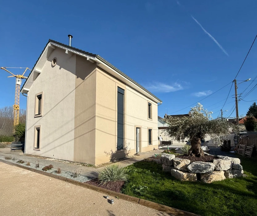 Façade d'immeuble résidentiel moderne avec porte d'entrée vitrée à carreaux et six fenêtres à volets roulants blancs disposées symétriquement sur deux étages