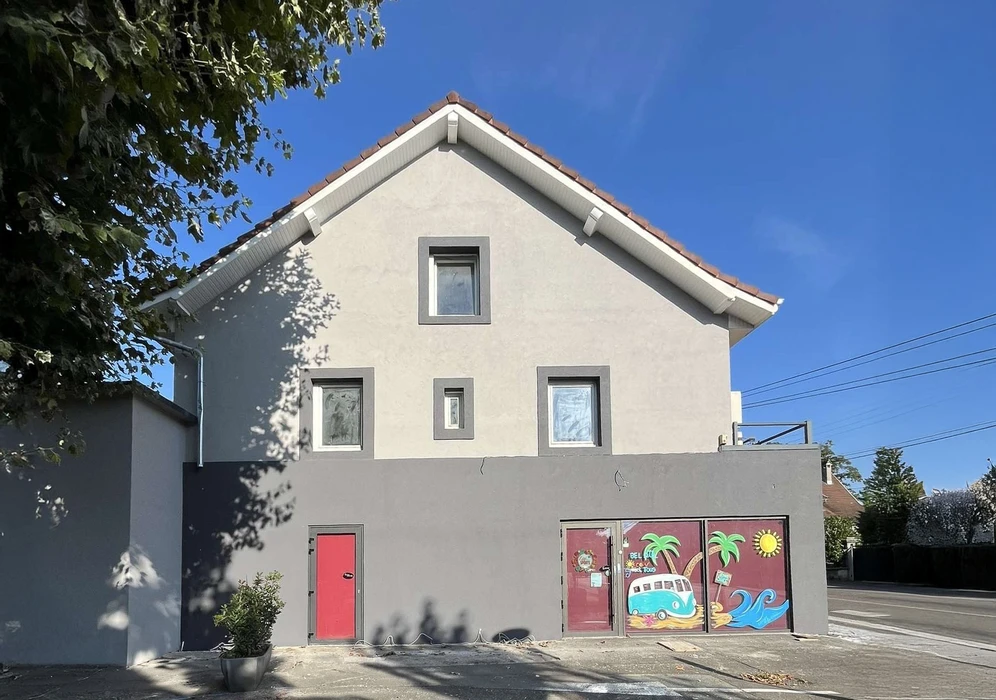 Façade d'immeuble résidentiel moderne avec porte d'entrée vitrée à carreaux et six fenêtres à volets roulants blancs disposées symétriquement sur deux étages